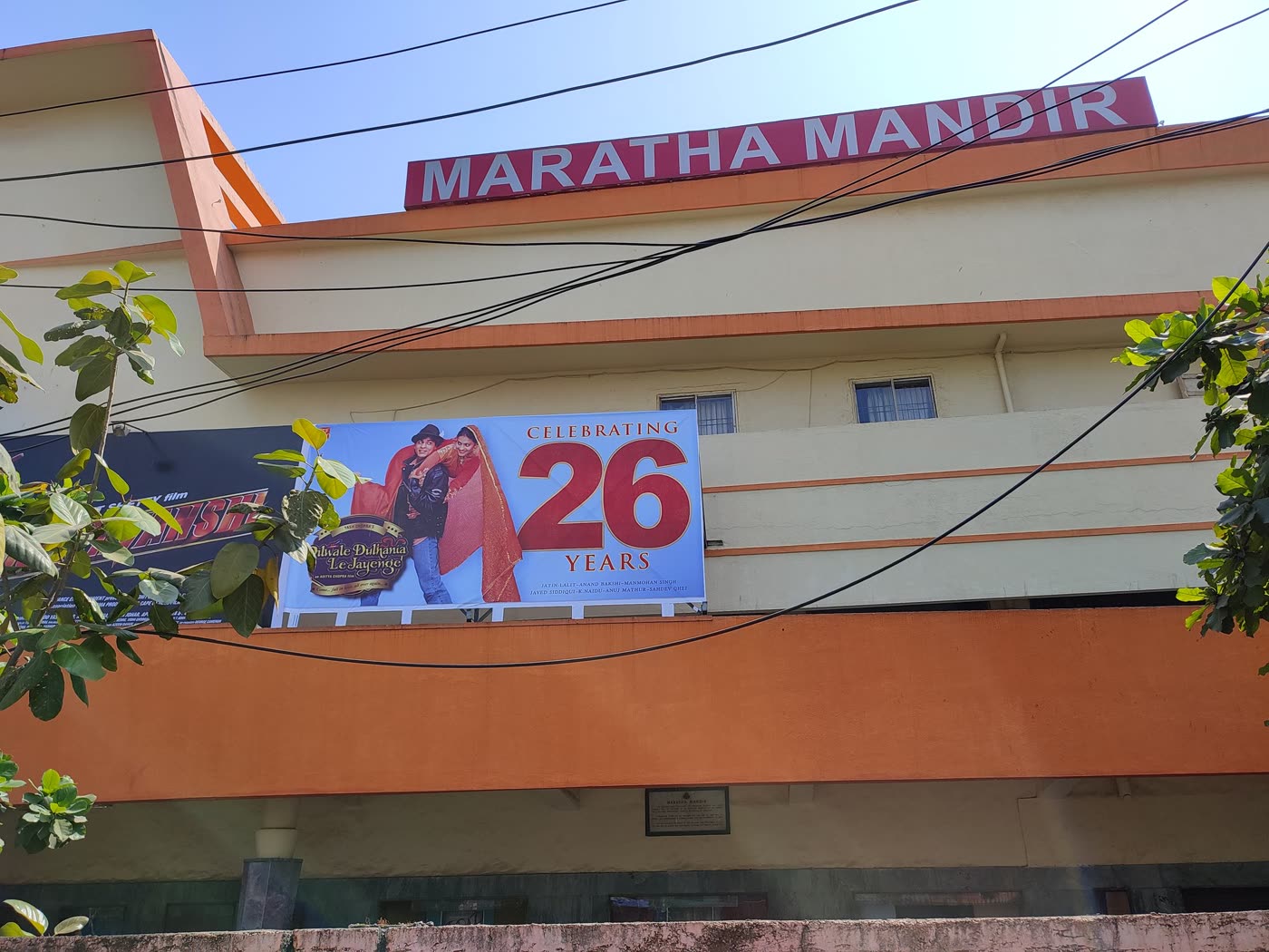 The front of the Maratha Mandir cinema in Mumbai, with a banner reading "Celebrating 26 Years" beside a poster for Dilwale Dulhania Le Jayenge.